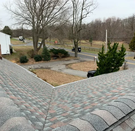 Roofer fixing damaged shingles on a roof.