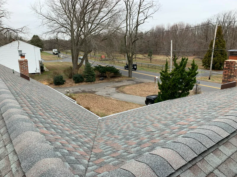 Roofer fixing damaged shingles on a roof.